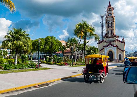 Motorcycle taxis on the road in front of a cathedral in the Plaza de Armas of Iquitos.