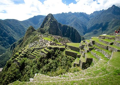 The ruins of Machu Picchu as seen from a lookout point above some agricultural terraces.