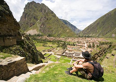 A tourist at the top of the impressive Ollantaytambo ruins, overlooking the town below.