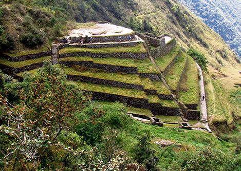 The ruins of Phuyupatamarca, with agricultural terraces, staircases and several buildings visible.