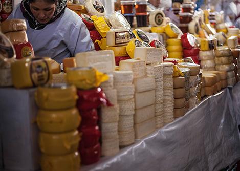 A vendor selling different varieties of cheese at the San Pedro Market in Cusco.