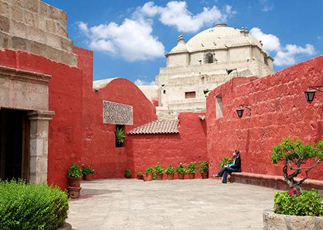 A visitor sitting on a bench in a small courtyard at the Santa Catalina Monastery in Arequipa.