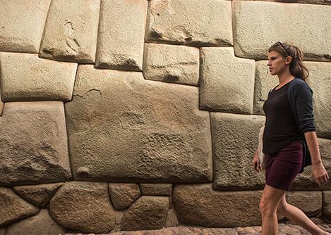 A woman walking past the twelve-angled stone, an impressive example of Inca stonework.