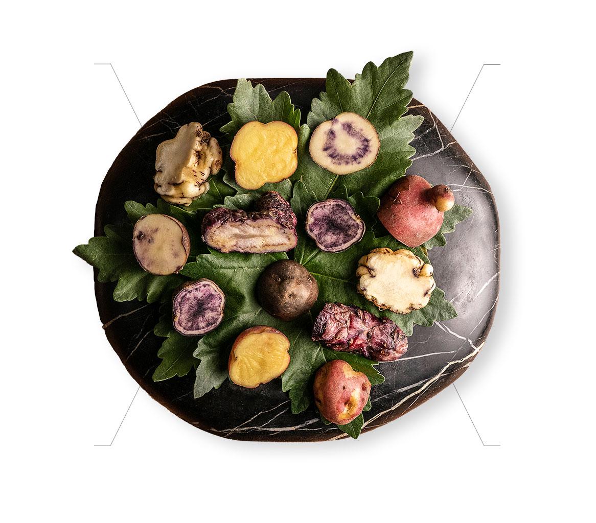 A selection of different native potato varieties, cut in half and displayed on a platter.