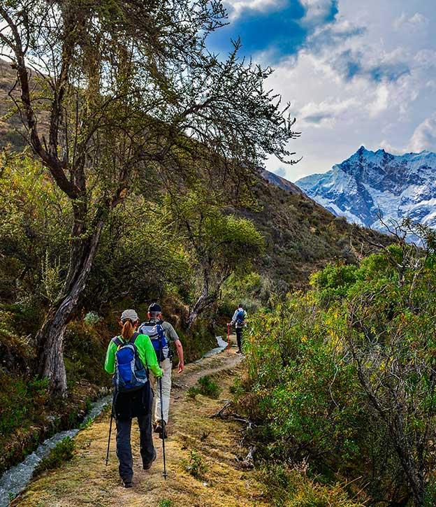 A group of hikers walking along the Inca Trail with a snow-capped mountain off in the distance.