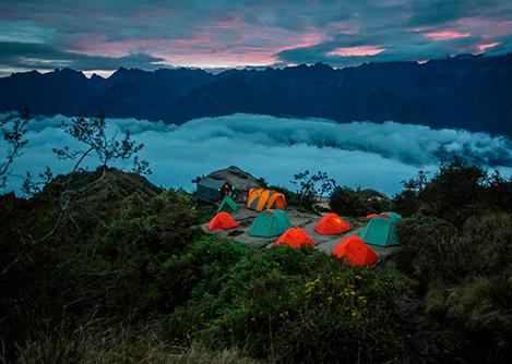 Several tents at a campsite on a clearing above thick clouds on the Inca Trail to Machu Picchu.
