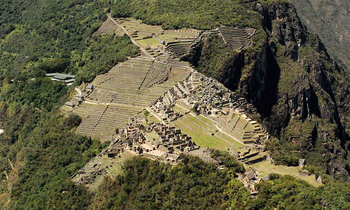 A close up of Machu Picchu taken from the top of Huayna Picchu on a clear and sunny day. The ruins are very visible.