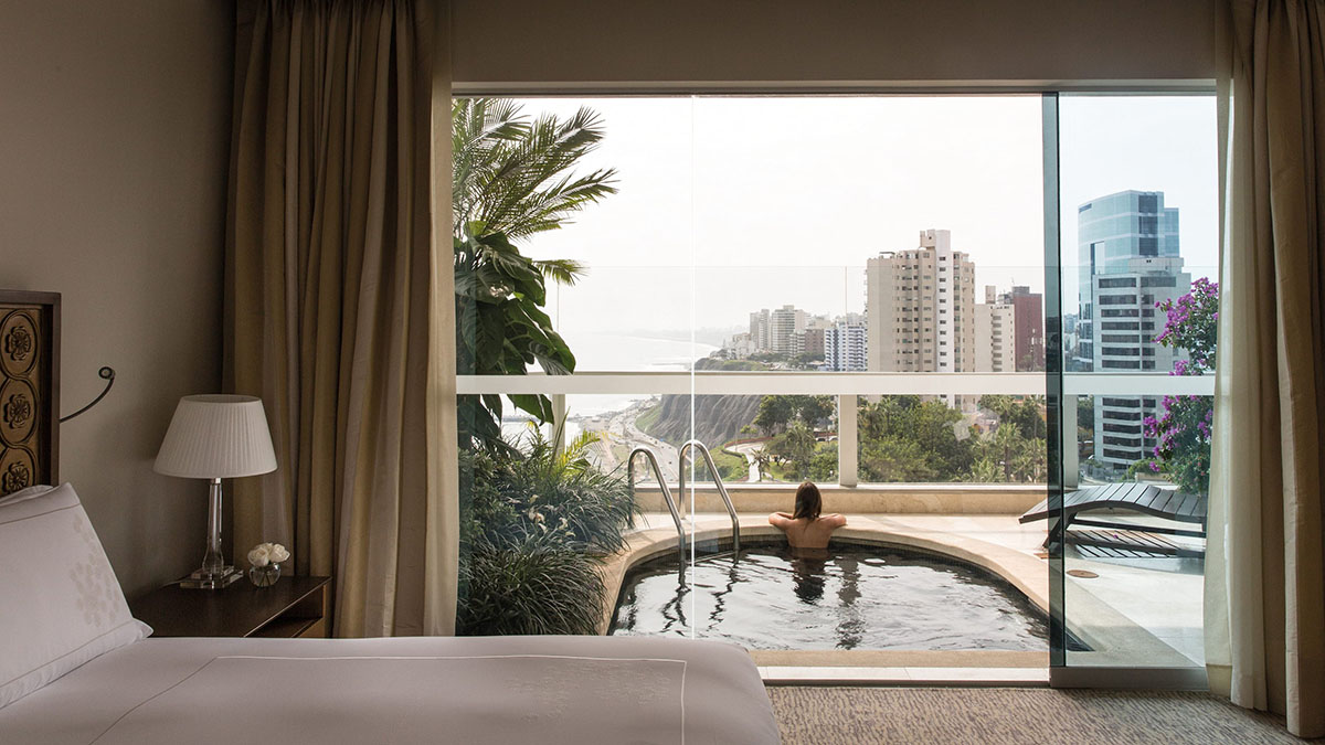 A woman soaks in her honeymoon suite's private pool looking out over the coast of Lima in Belmond Miraflores Park.