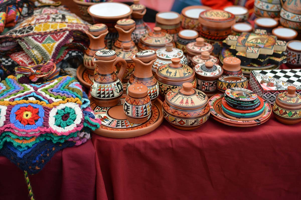 Alpaca wool hats and painted clay bowls and other Peruvian handicrafts at a Cusco market.